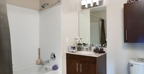 A bathroom with a bathtub, a shower, a sink, and a mirror.