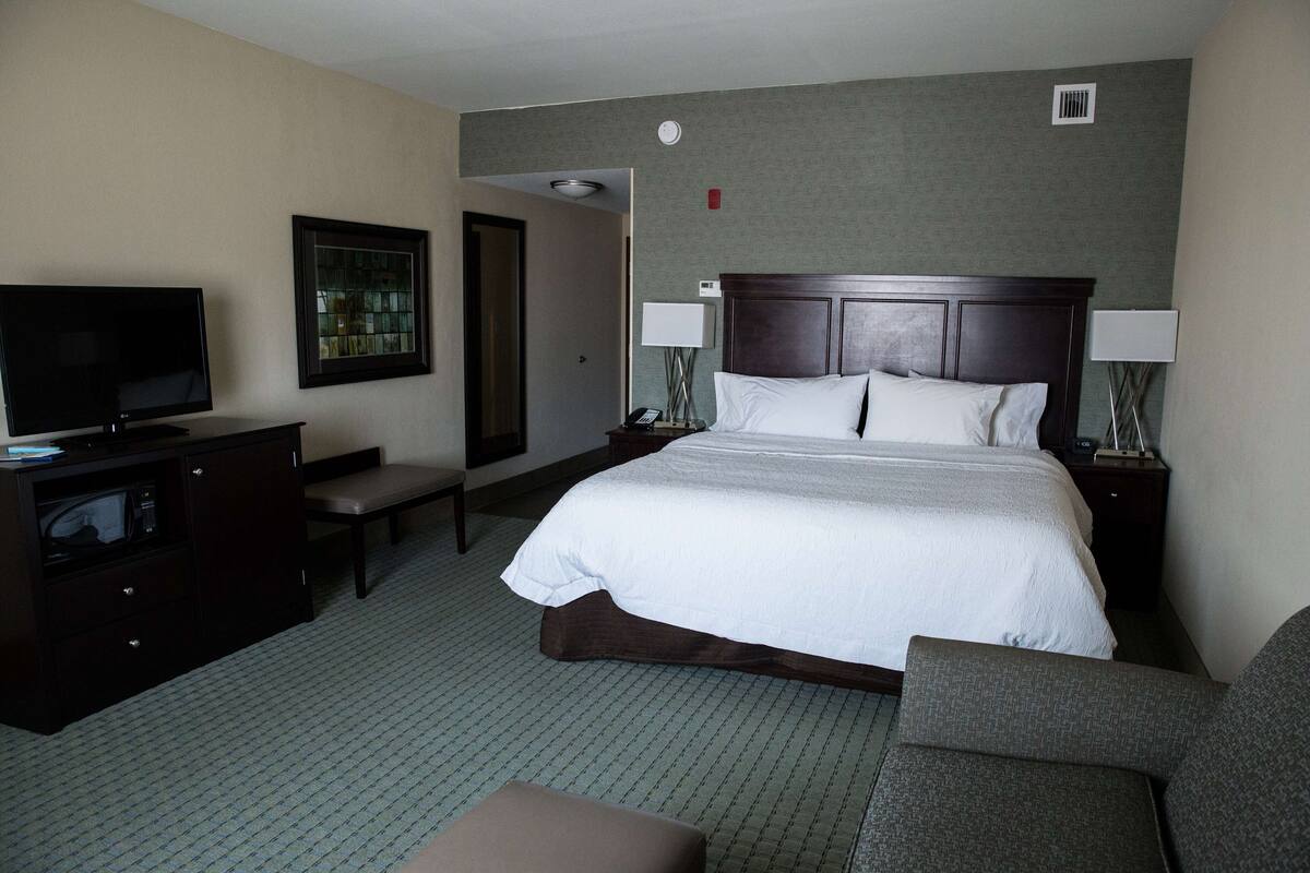 A hotel room with a large bed, a television, a desk, and a chair.