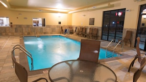 An indoor swimming pool with a glass table and chairs, a tiled floor, and a view of the outside through a glass door. - Hampton Inn & Suites Bismarck Northwest (Bismarck)