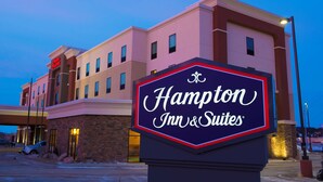 A Hampton Inn & Suites sign in front of a hotel building with a flat roof and multiple windows. - Hampton Inn & Suites Bismarck Northwest (Bismarck)