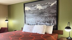 Habitación de hotel con una cama grande, dos lámparas de noche, un cuadro colgado de un paisaje montañoso y una pared verde.