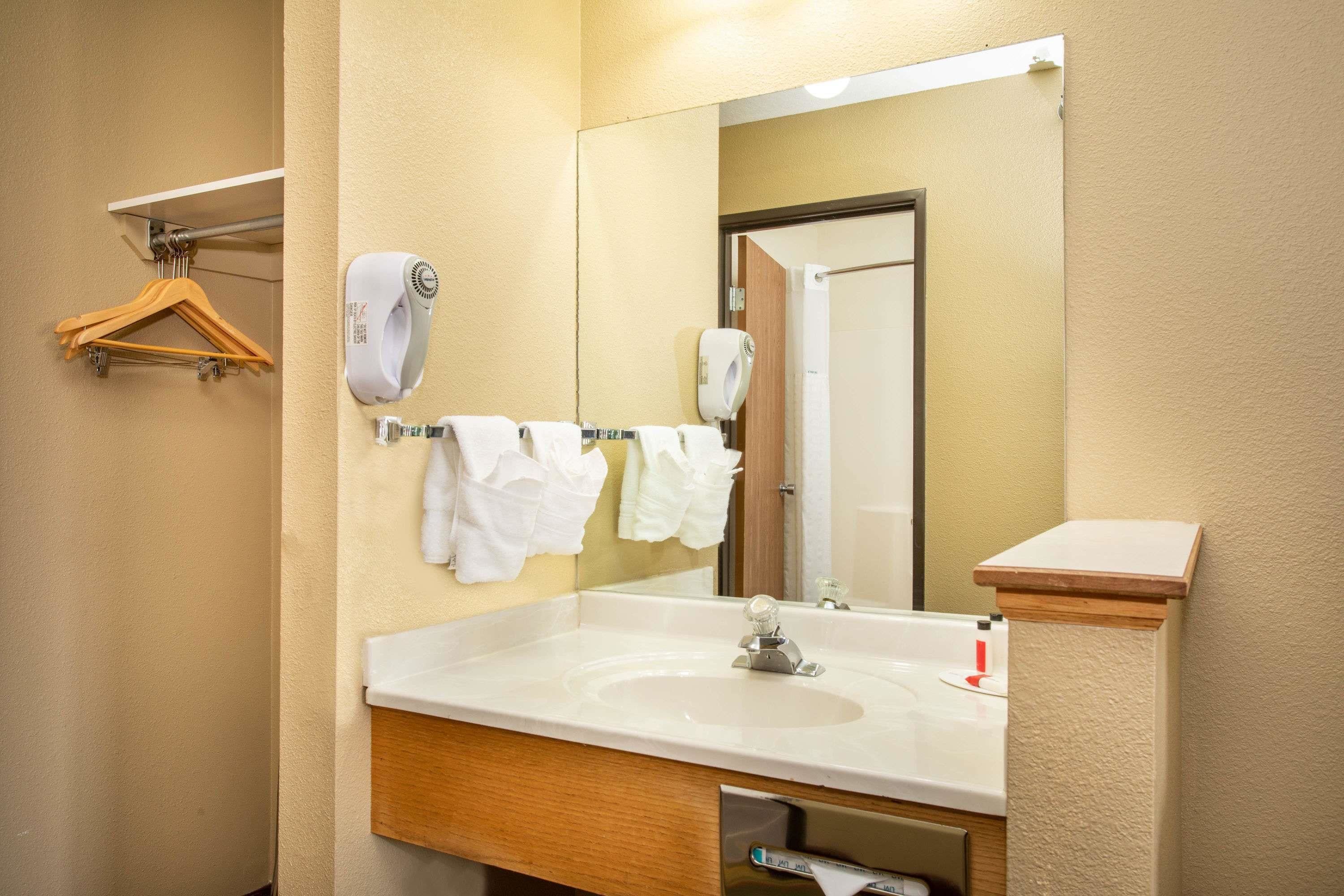 Un baño con lavabo, espejo, toallero y secamanos.