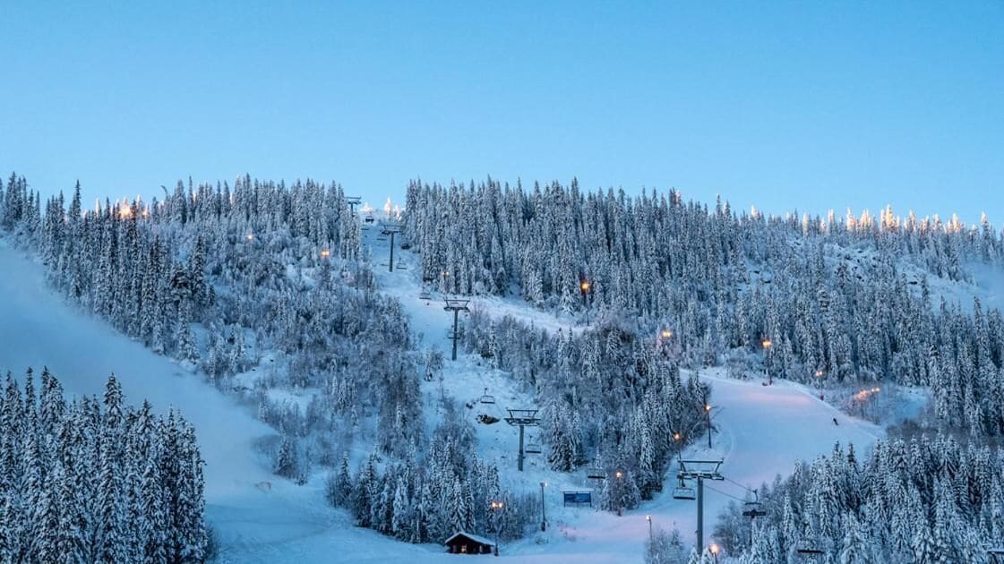 A snow-covered ski resort with ski lifts, a chairlift, and a cabin.