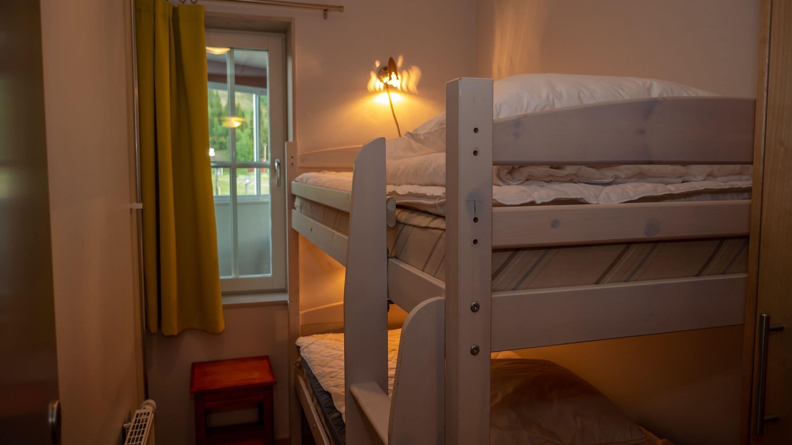 Habitación con literas, una ventana, una mesita y un calefactor.