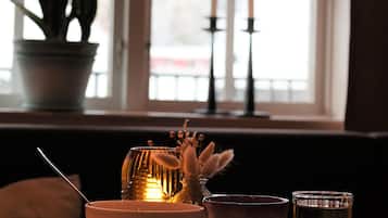 A dining table with plates of food, a candle, and a potted plant by a window.