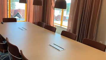 A conference room with a long table, brown chairs, and pendant lights.