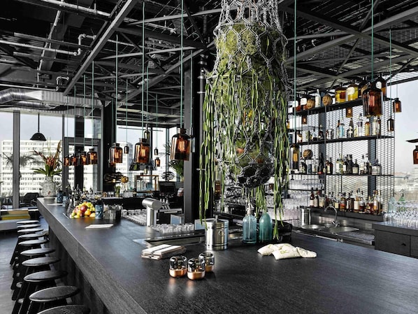 En bar med högt i tak, industriell design och utsikt över stadsbilden.