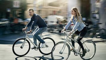 Dos personas andando en bicicleta por una calle de la ciudad.