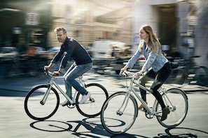 Dos personas andando en bicicleta por una calle de la ciudad.