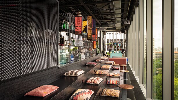 Et hotel lobby med en lang receptionsdisk, komfortable siddepladser og udsigt over byen gennem store vinduer.