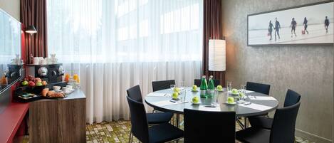 Habitación de hotel con comedor que incluye una mesa redonda, sillas y alimentos para el desayuno.