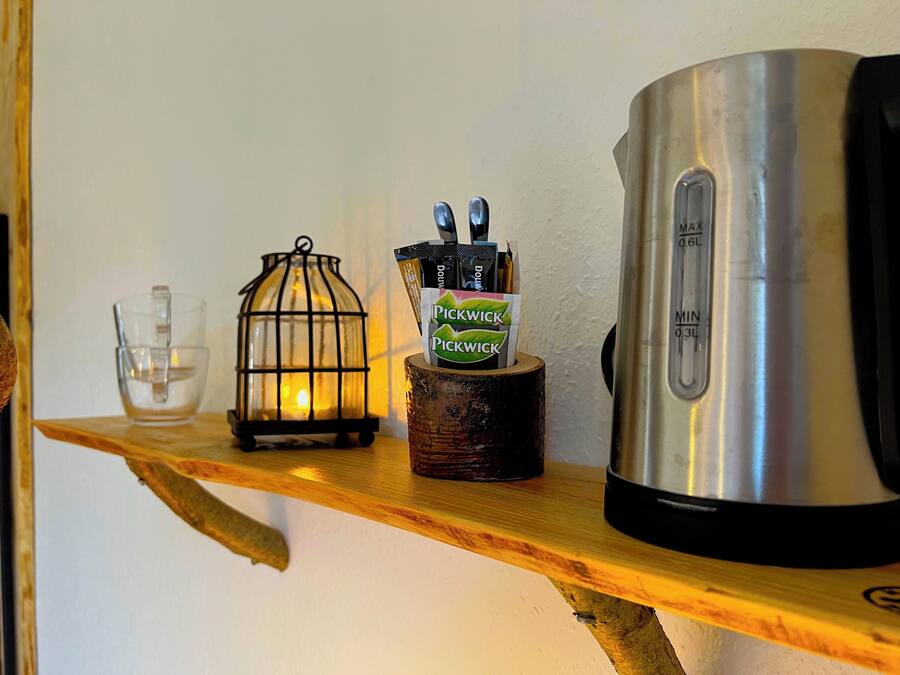 Una repisa con un farol, una cafetera y una taza.