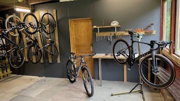 Una tienda de reparación de bicicletas con varias bicicletas, herramientas y una puerta de madera.