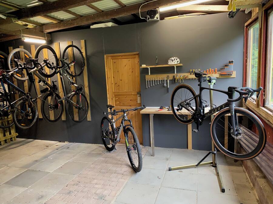 Una tienda de reparación de bicicletas con varias bicicletas, herramientas y una puerta de madera.