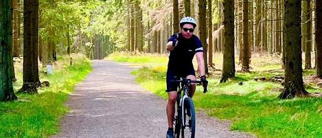 A cyclist on a paved path surrounded by trees.