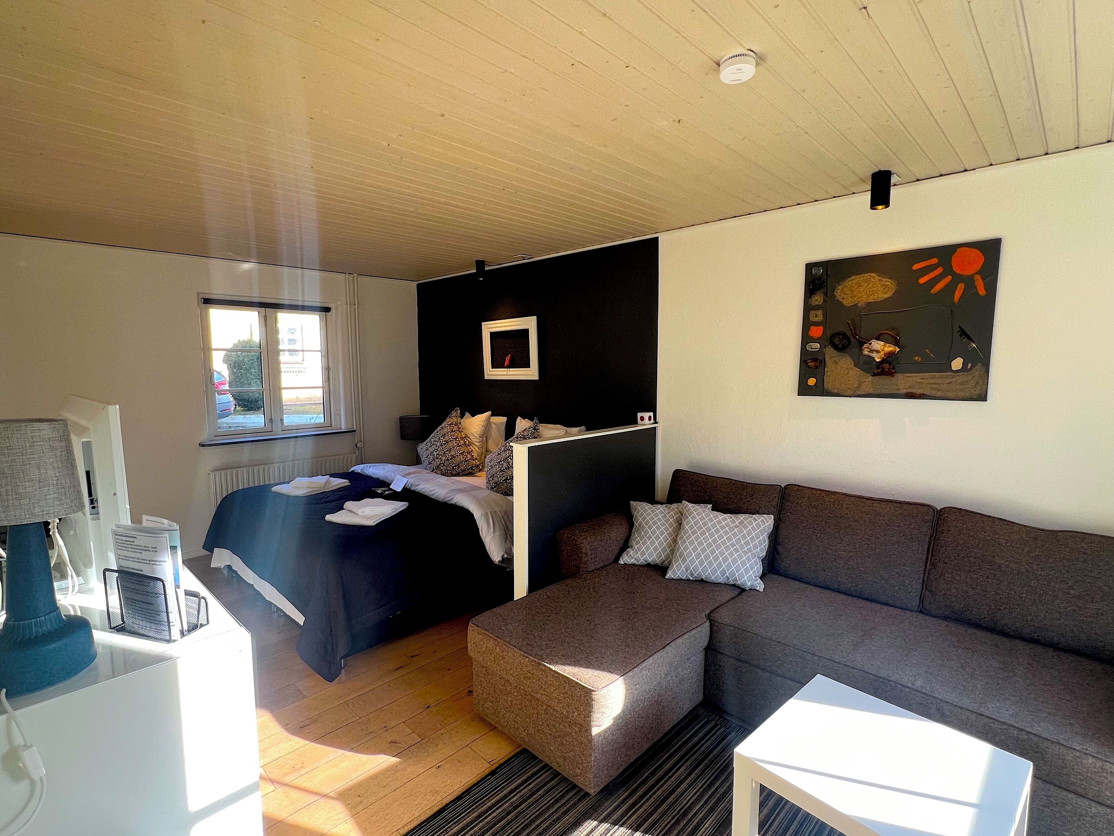 A modern bedroom with a bed, a sofa, a desk, and a window.