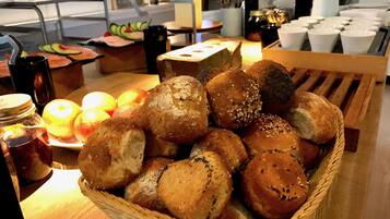 A basket of assorted bread rolls and sliced apples on a table.