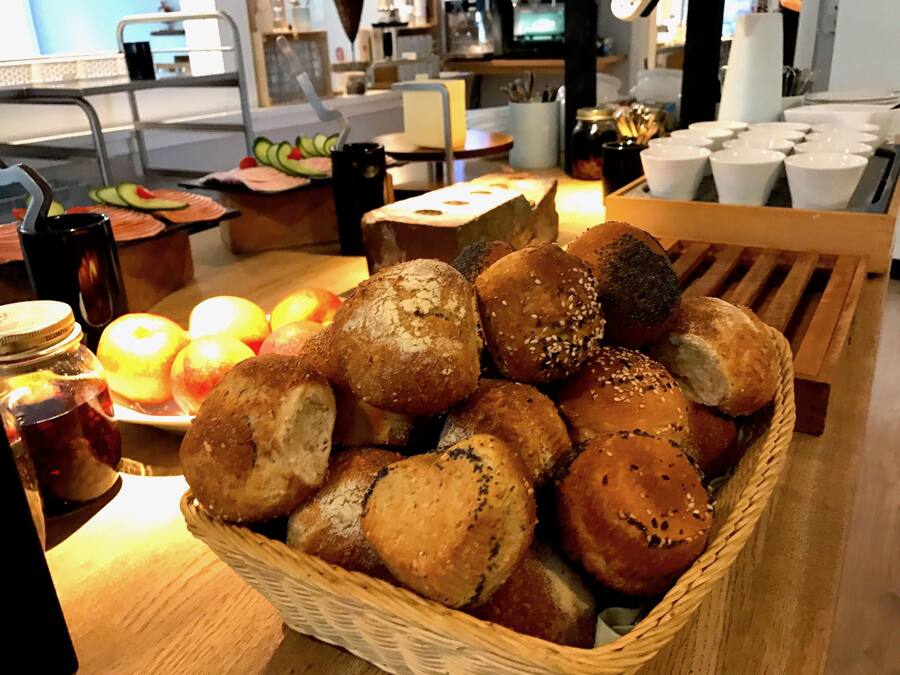 A basket of assorted bread rolls and sliced apples on a table.