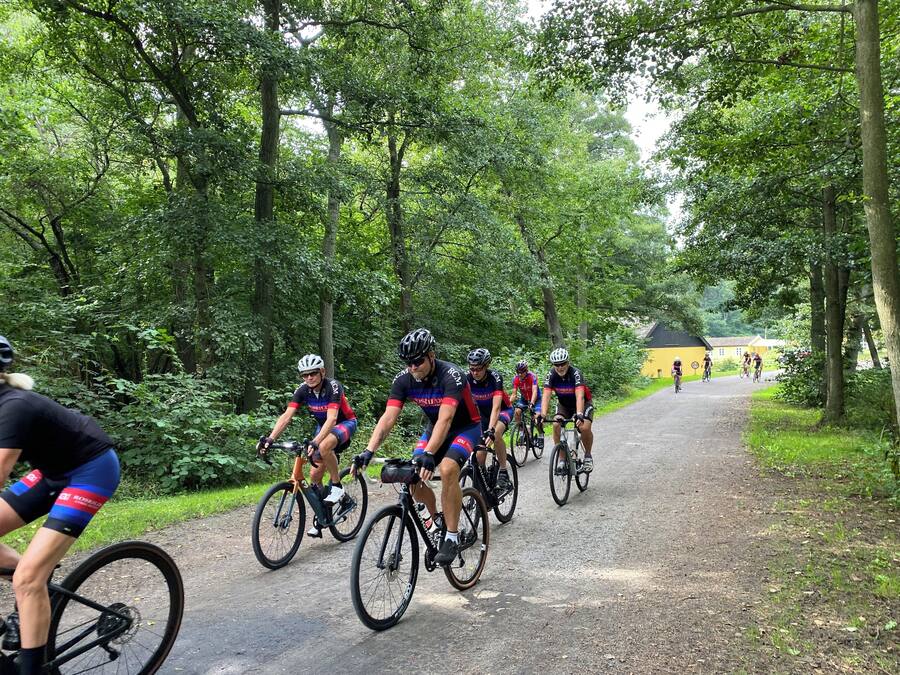 Un grupo de ciclistas en un camino de tierra rodeado de árboles.