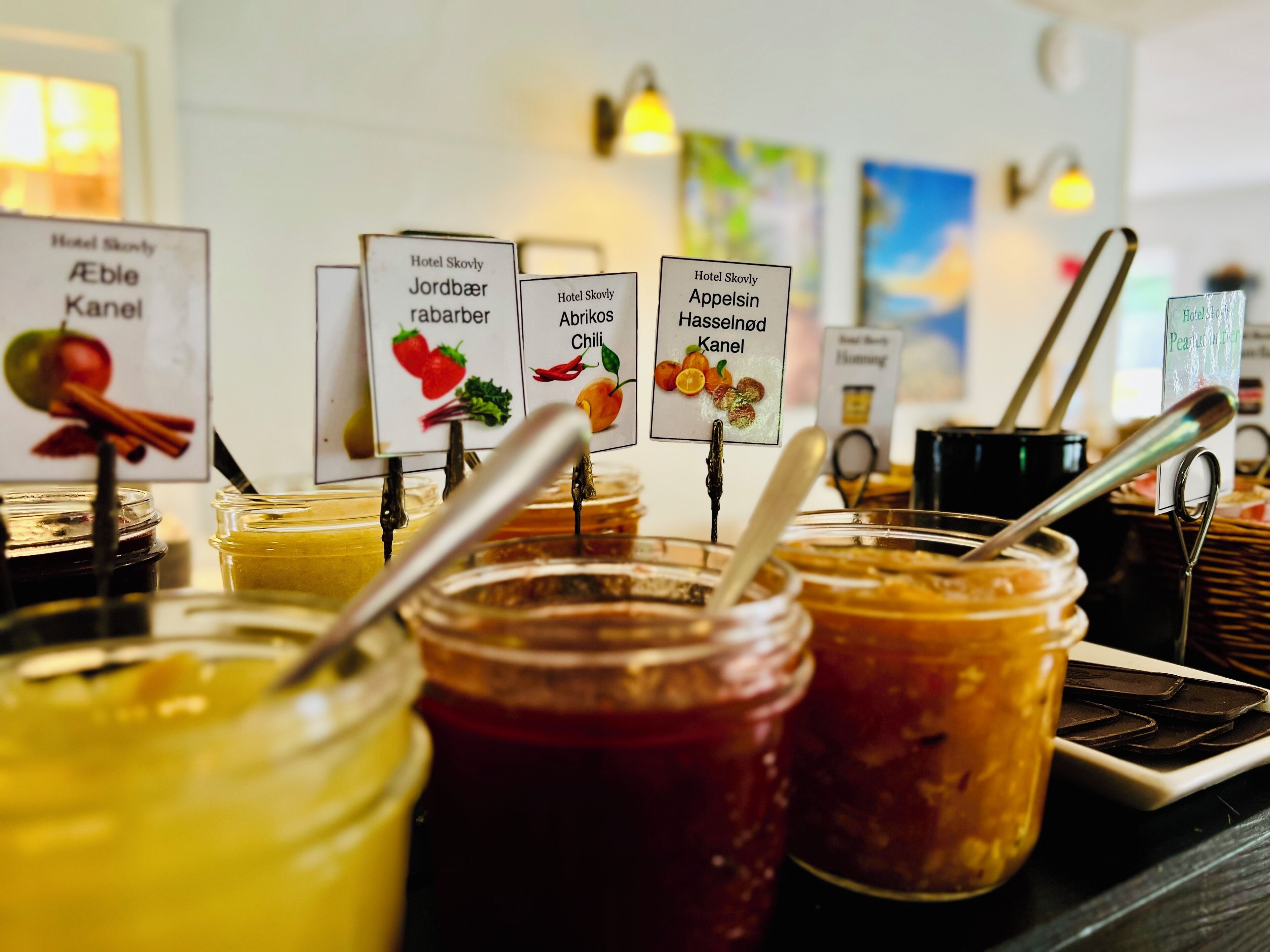 Variedad de frascos con etiquetas que indican diferentes conservas y salsas, como manzana, fresa y chile.