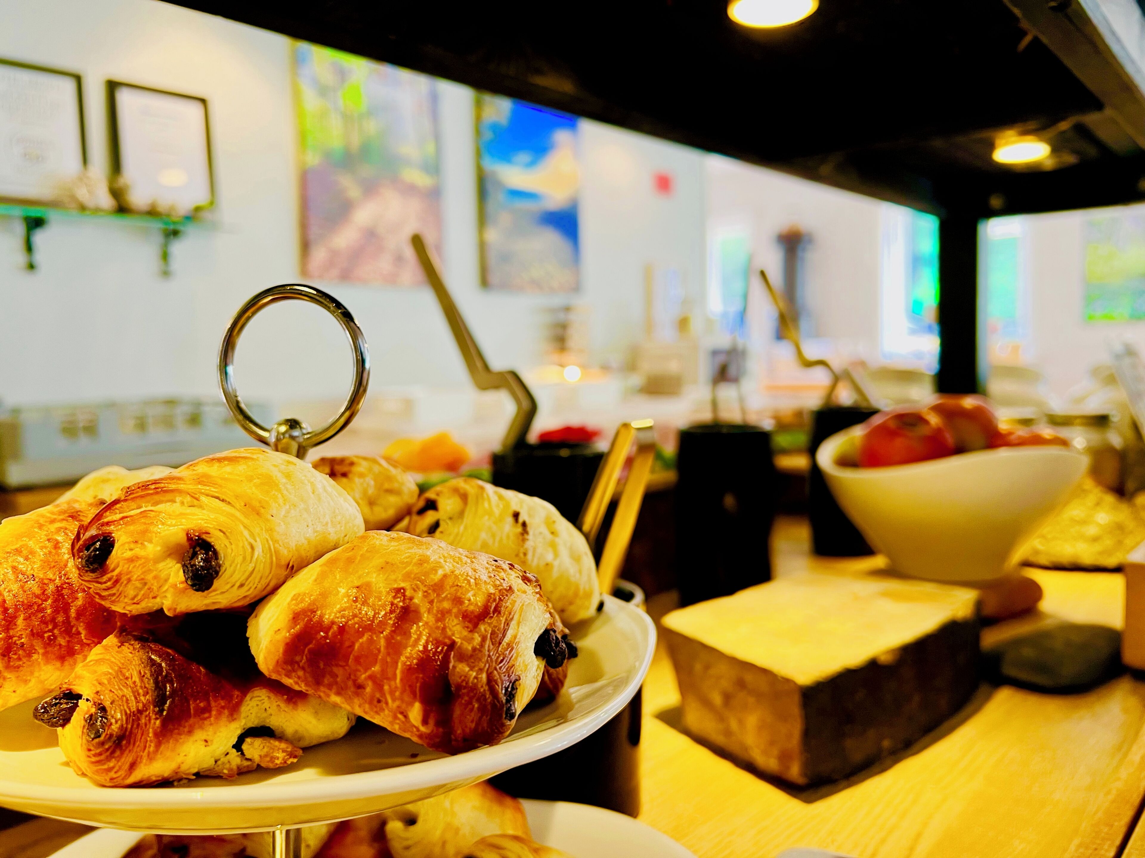 Una mesa de buffet con pasteles, un bol de fruta y un bloque de queso.