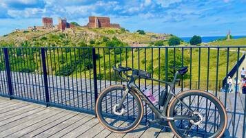 Una bicicleta estacionada en una terraza de madera, con una vista de un castillo histórico al fondo.