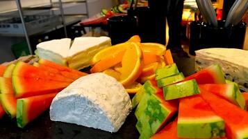 A buffet table with various food items including watermelon, cheese, and orange slices.