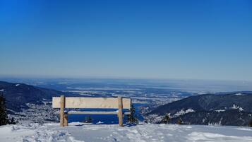 A wooden bench on a snowy hill overlooking a valley.