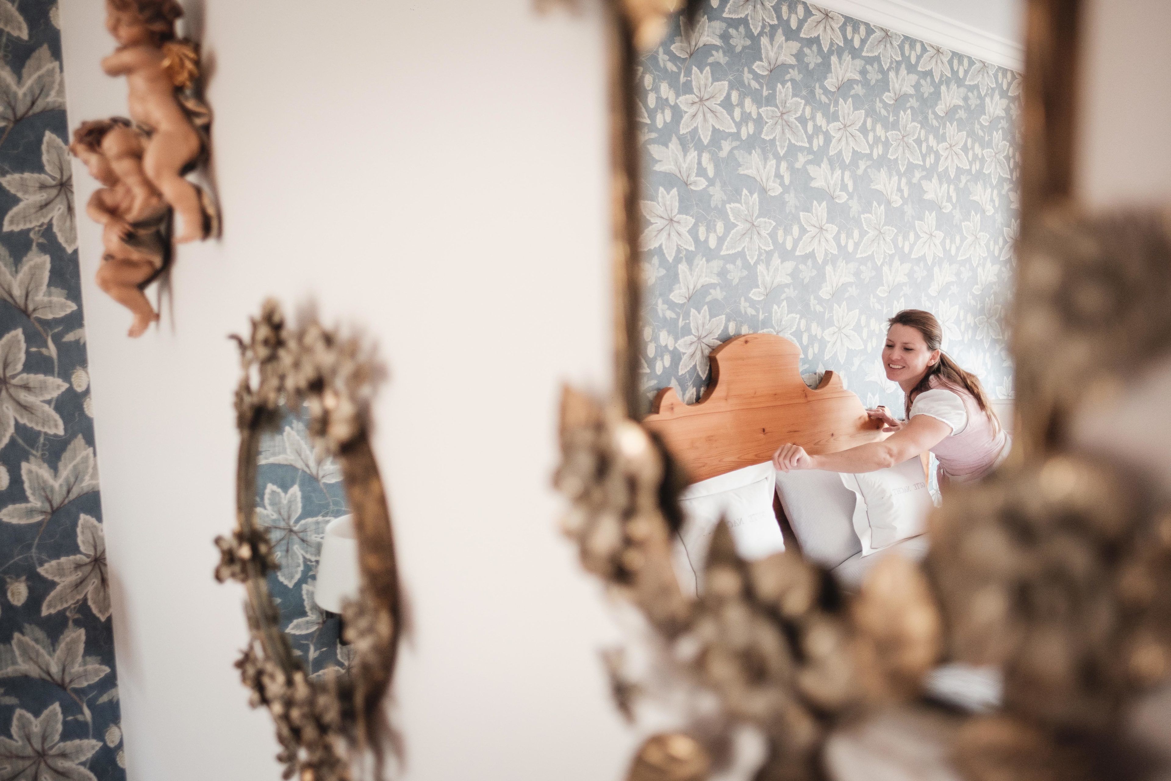 A room with floral wallpaper, a wooden piano, and decorative mirrors.
