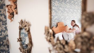 A room with floral wallpaper, a wooden piano, and decorative mirrors.