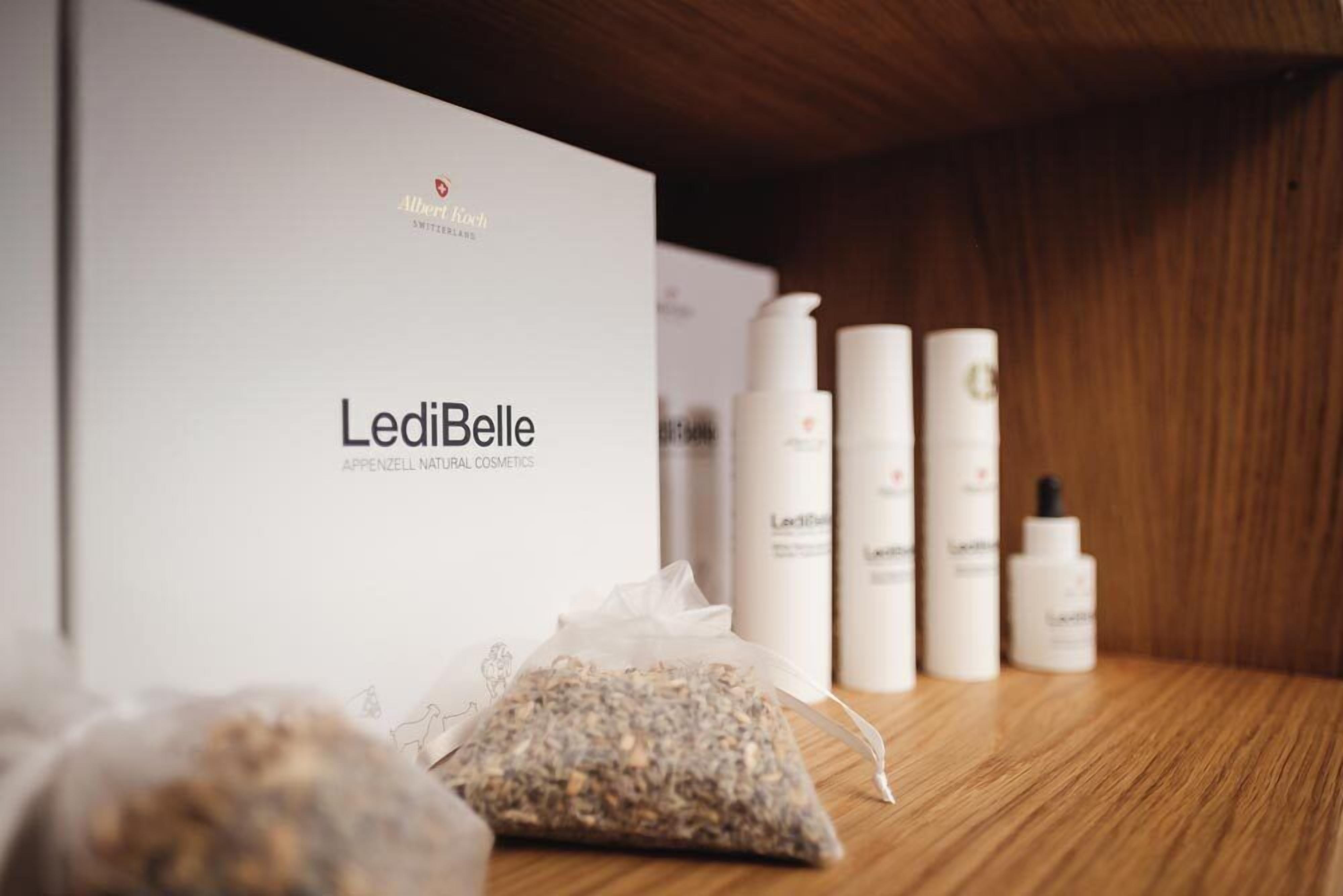 Ein Holzregal mit einer Kiste mit der Aufschrift 'Ledibelle' und mehreren Hautpflegeflaschen.