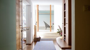 A hallway with a wooden floor, a blue rug, and a chair with a geometric pattern. - Landhaus Am Stein Tegernsee (Bad Wiessee)