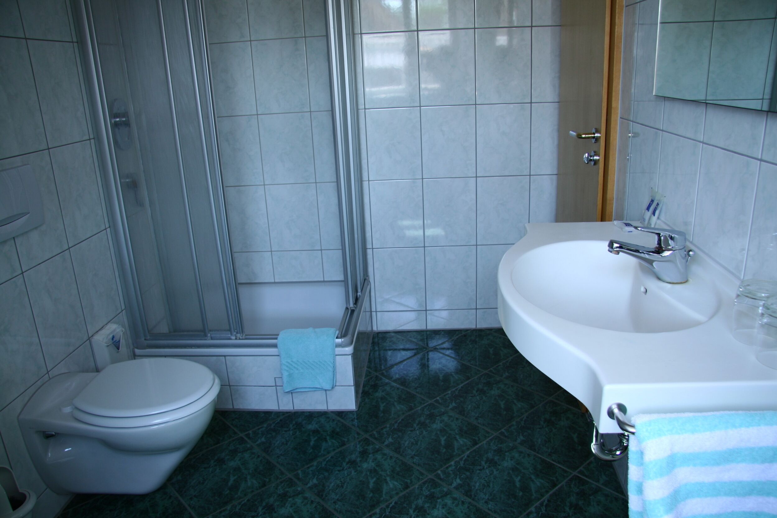 A bathroom with a toilet, shower, and sink.