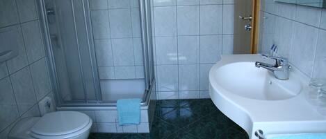 A bathroom with a toilet, shower, and sink.