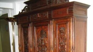 Un mueble de madera grande y ornamentado con elaborados grabados y varios cajones.
