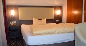 A hotel room with a large bed, two bedside tables, a headboard, and wall-mounted lamps. - Thermen Hotel Bad Soden am Taunus (Bad Soden am Taunus)