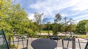 A view from a balcony with a table and chairs, overlooking a parking area and trees. - Thermen Hotel Bad Soden am Taunus (Bad Soden am Taunus)