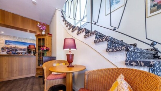 Une pièce chaleureuse avec un canapé en osier, une petite table ronde et une lampe.