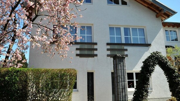 A two-story house with a symmetrical facade, large windows, and a stone pillar. - Pension Bella Vista (Bochum)