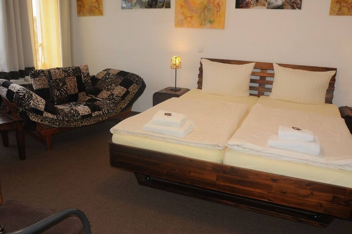A hotel room with a large bed, a chair with a zebra print cushion, and artwork on the walls.