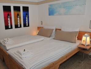 A double bed with white linens and a nightstand with a lamp. - Pension Bella Vista (Bochum)
