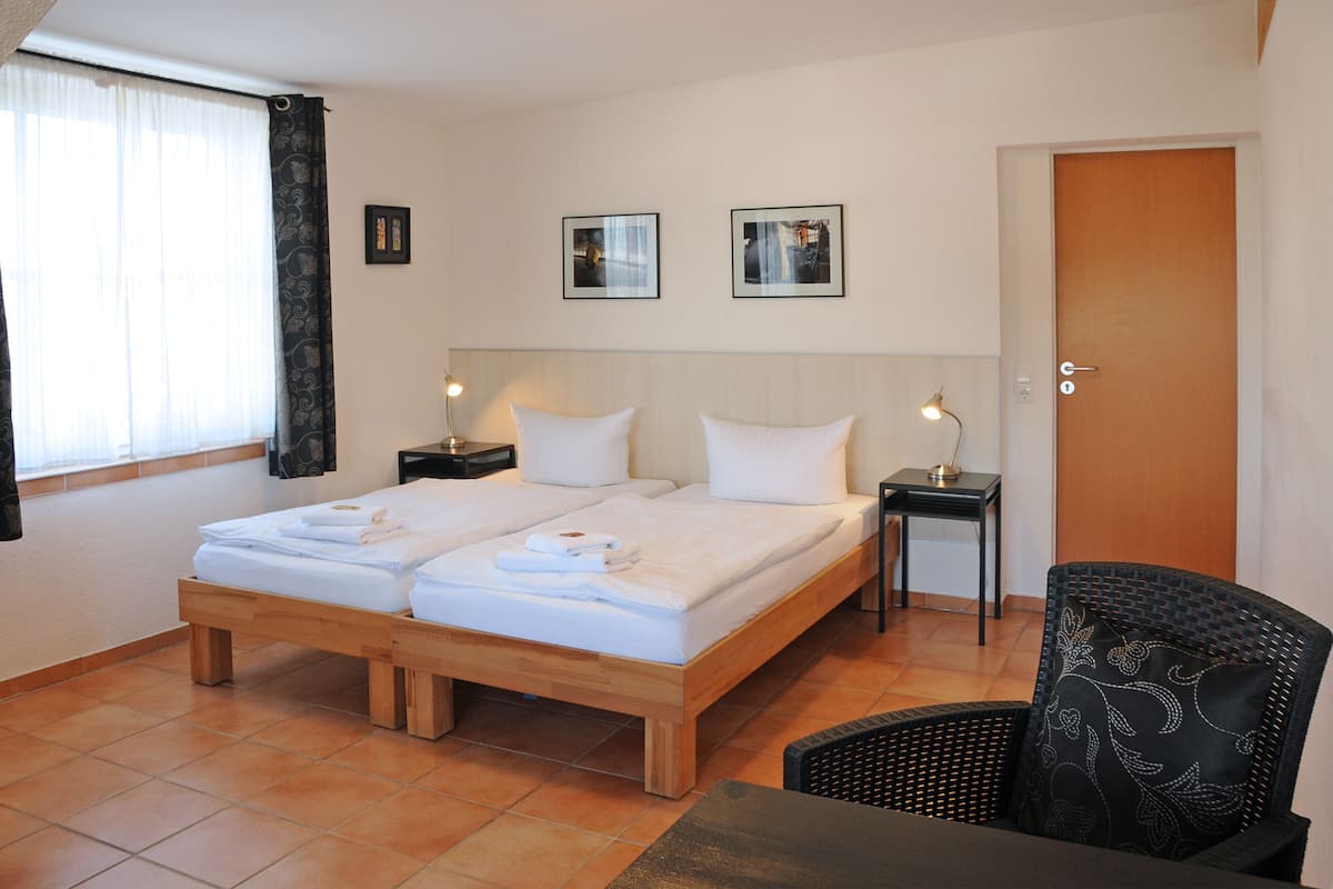 A double bed with white linens, two bedside tables, a chair, and a door.