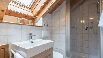 A modern bathroom with a skylight, a shower, and a wooden vanity.