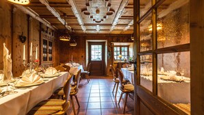 Un restaurant au décor intérieur en bois, avec de longues tables dressées pour le repas, et une vue sur un paysage enneigé par les fenêtres.