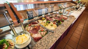 Ein reichhaltiges Buffet mit verschiedenen Speisen, darunter Fleisch, Käse und Obst.
