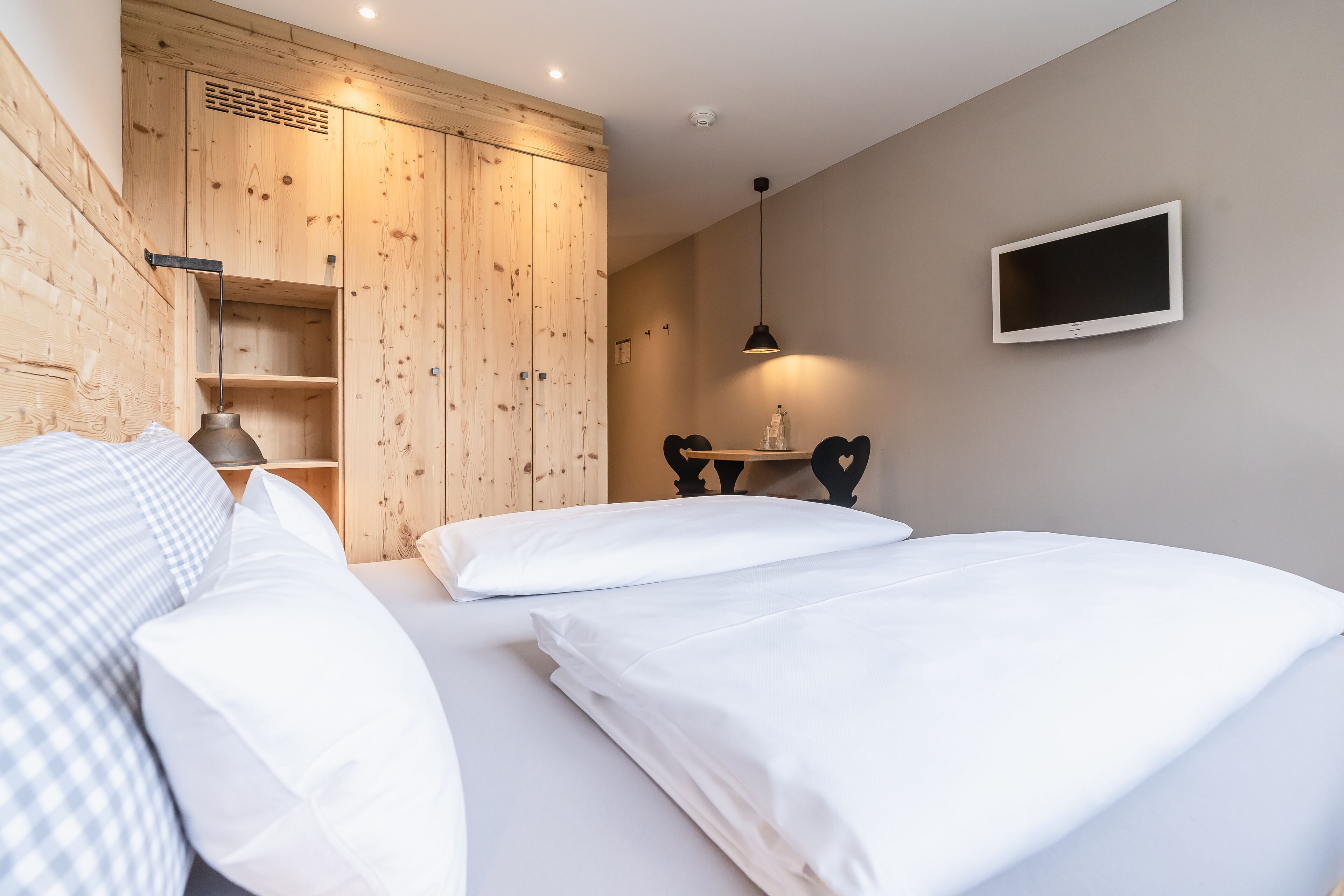 Un dormitorio con dos camas, un armario de madera y un televisor en la pared.