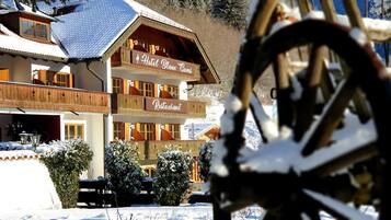 Un hôtel doté d’un restaurant au rez-de-chaussée, de balcons en bois et entouré d’un paysage enneigé.