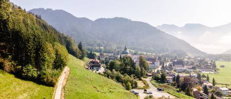Un village rural avec une église imposante, entouré de collines verdoyantes et sous un ciel dégagé.