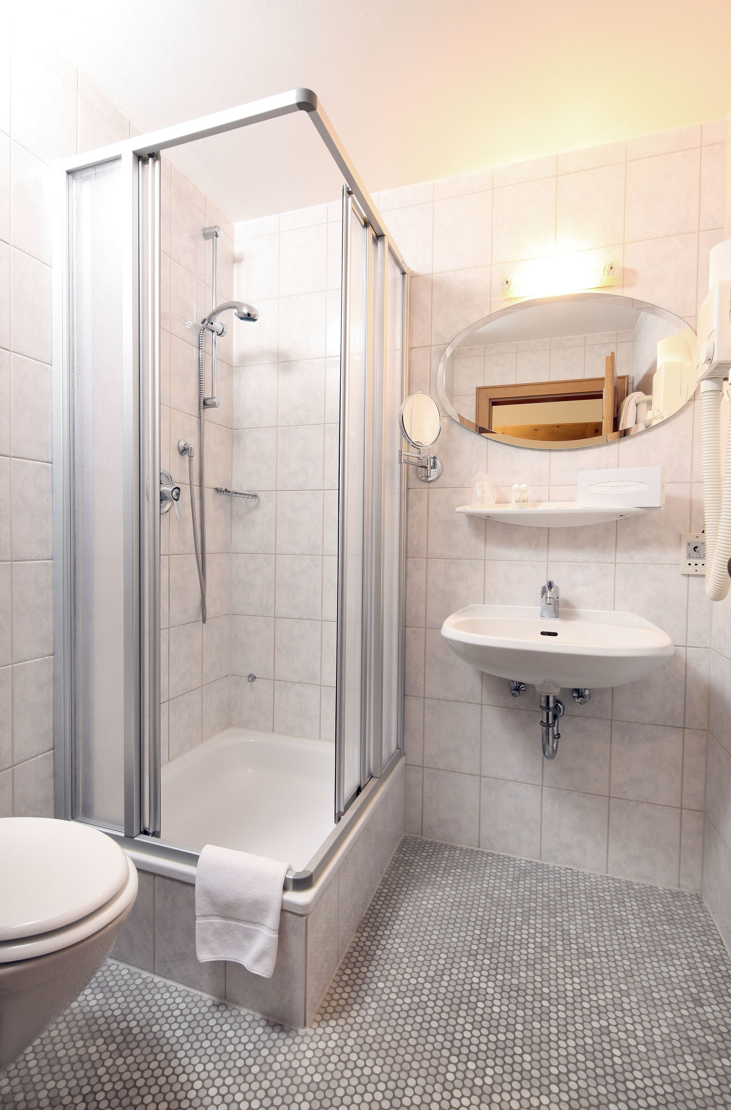 A bathroom with a glass-enclosed shower, a sink with a mirror above it, and a toilet.