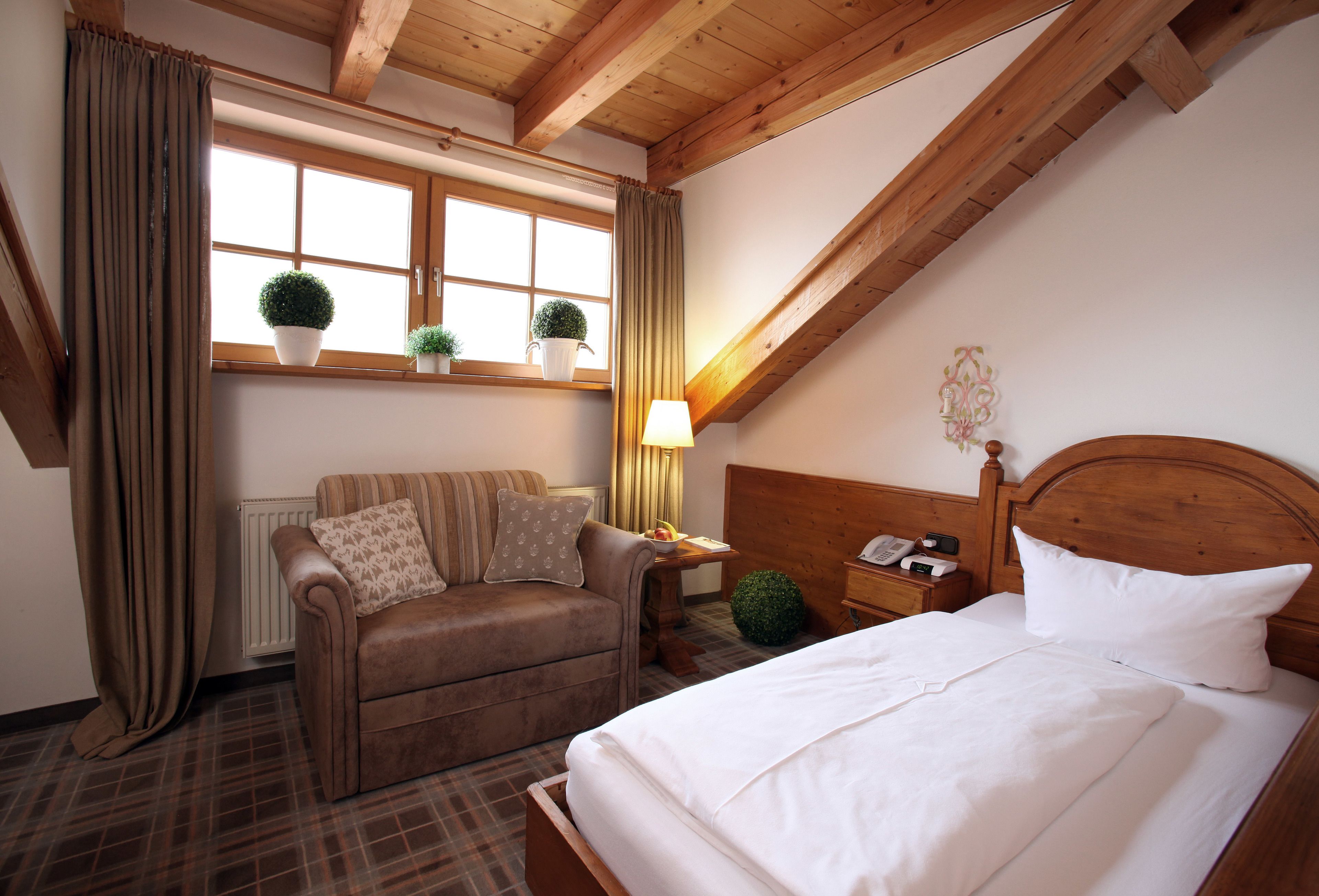 A cozy room with a bed, a sofa, a window with curtains, and a radiator.